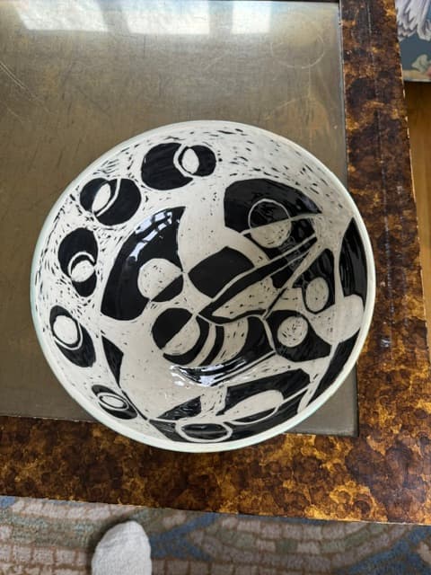 Top-down view of a ceramic bowl featuring bold, hand-painted black and white abstract patterns.