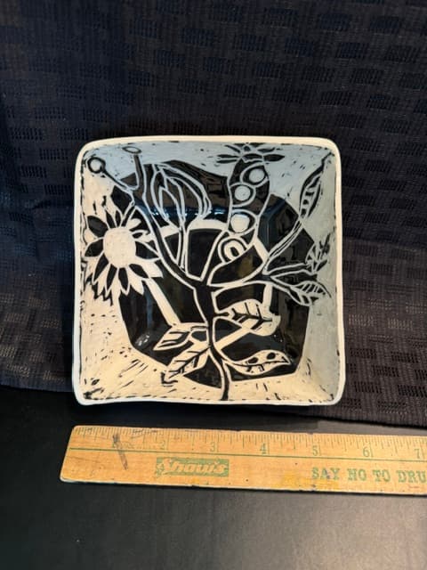 Square ceramic dish with black and white botanical patterns, shown next to a wooden ruler.