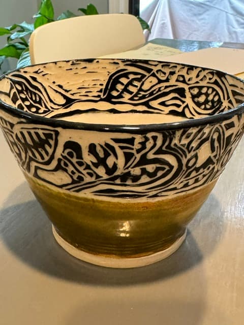 Ceramic bowl with intricate black and white sgraffito patterns and a mossy green base.