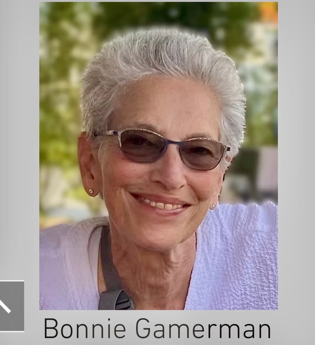 Smiling portrait of Bonnie Gamerman, a woman with short white hair and tinted glasses.